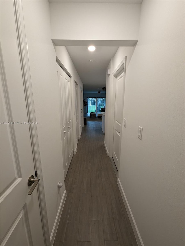 hall with dark wood-style floors and baseboards