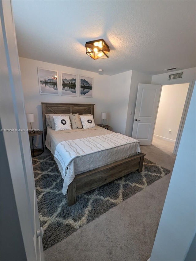 bedroom featuring visible vents, carpet flooring, and a textured ceiling