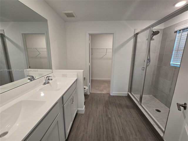6001 Woods Edge Cir, Riviera Beach, FL 33410 - bathroom featuring double vanity, a shower stall, a spacious closet, and wood finished floors