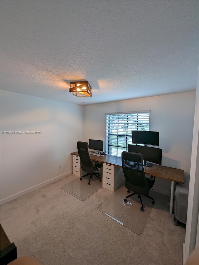 carpeted office space with a textured ceiling and baseboards