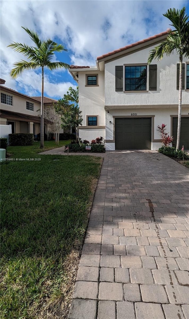 view of front of home with a garage, a front lawn, decorative driveway, and stucco siding