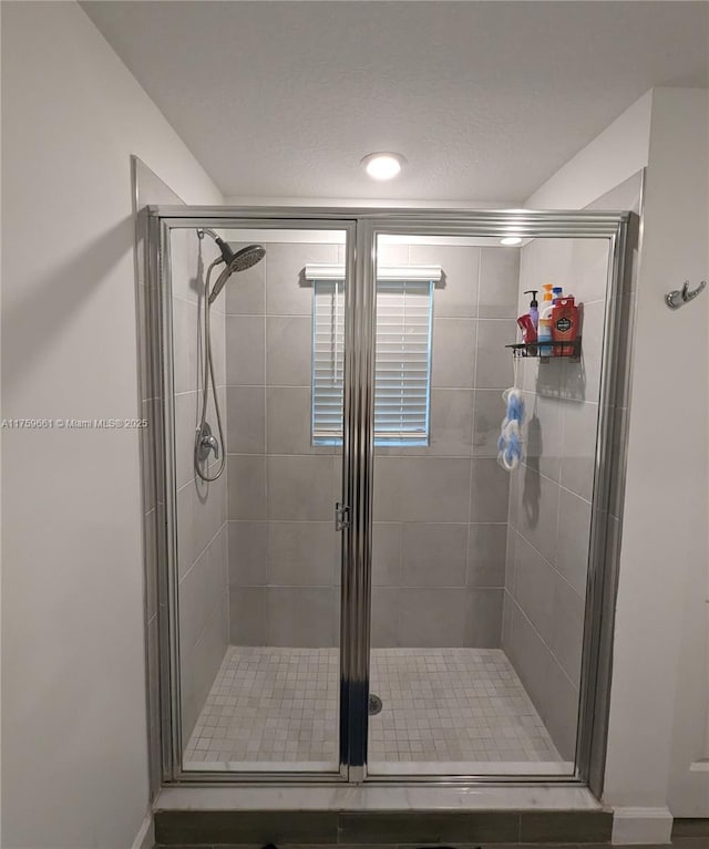 bathroom with a shower stall and a textured ceiling