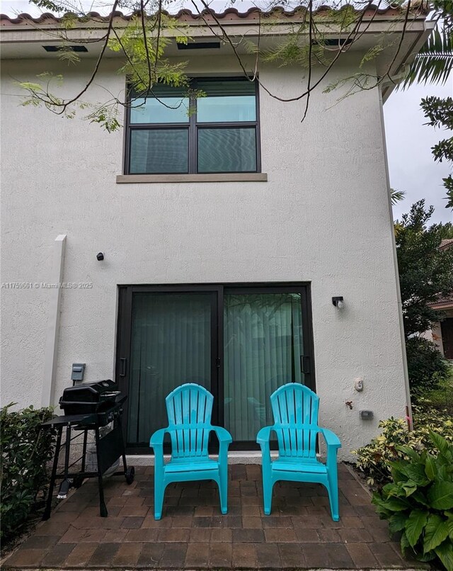 rear view of property featuring a patio and stucco siding