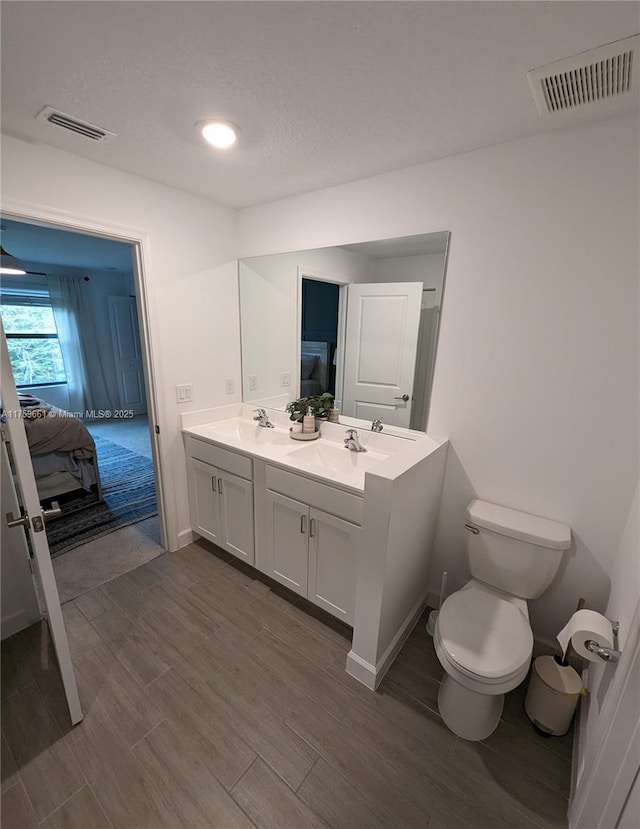 bathroom with ensuite bath, visible vents, a sink, and wood finished floors