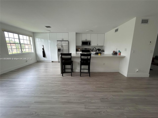 kitchen featuring stainless steel appliances, light countertops, visible vents, and a peninsula