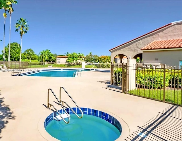 community pool with a patio area and fence