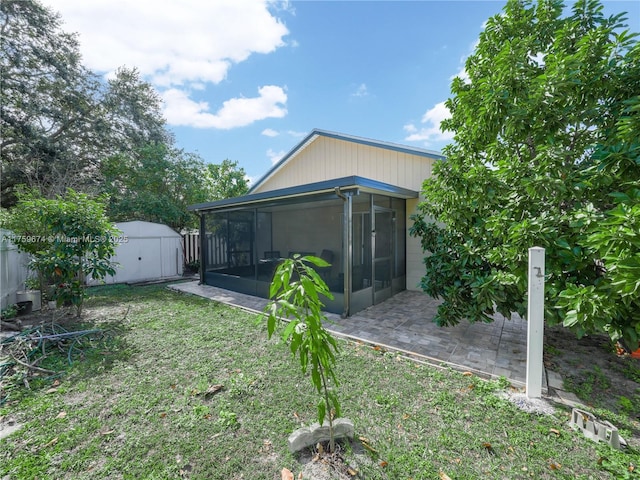 rear view of property with a yard, a storage unit, a sunroom, fence, and an outdoor structure