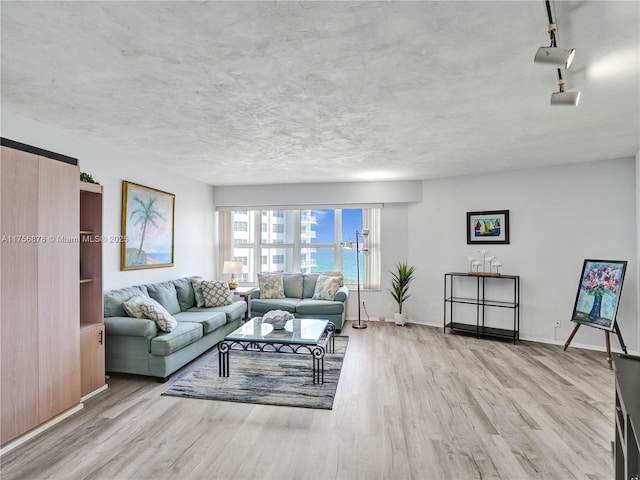 living room featuring a textured ceiling, wood finished floors, and baseboards