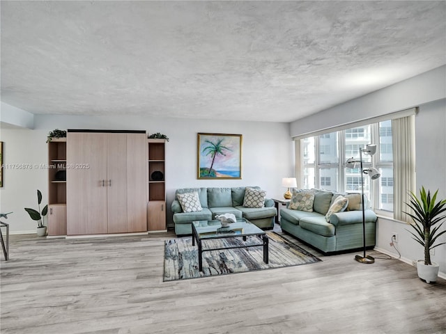 living room featuring light wood-style floors, baseboards, and a textured ceiling