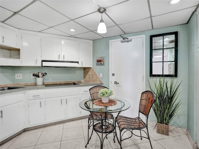 kitchen with light tile patterned flooring, black electric cooktop, under cabinet range hood, white cabinets, and light countertops