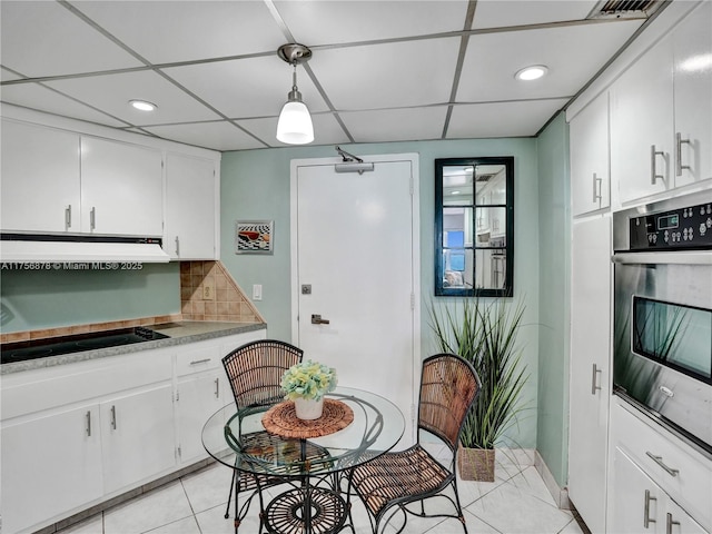 kitchen with white cabinets, a drop ceiling, black electric stovetop, ventilation hood, and stainless steel oven