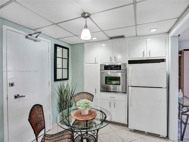 kitchen with freestanding refrigerator, white cabinetry, stainless steel oven, and a paneled ceiling