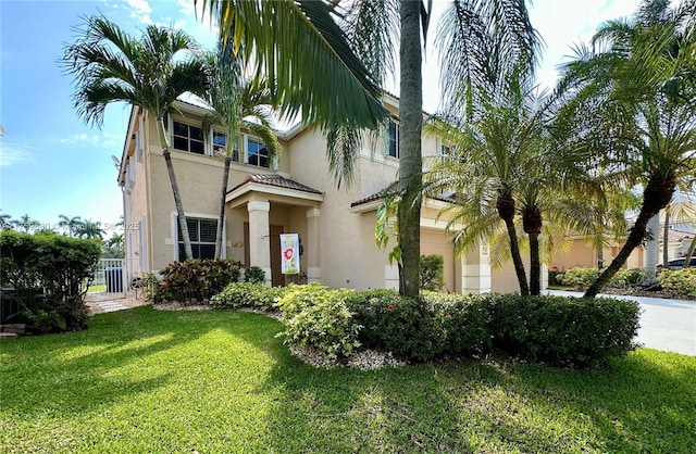 mediterranean / spanish home with a front yard, concrete driveway, an attached garage, and stucco siding