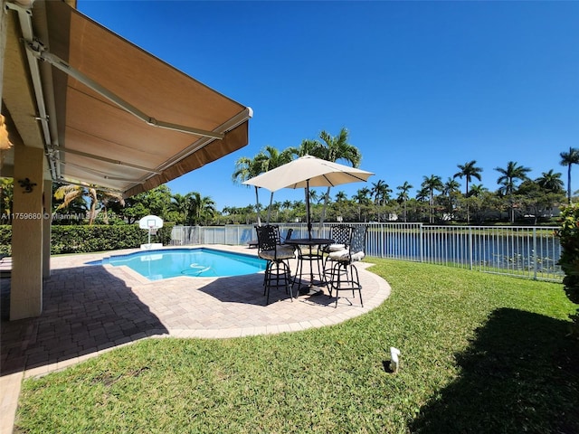 view of swimming pool with a patio, a fenced backyard, a water view, and a lawn