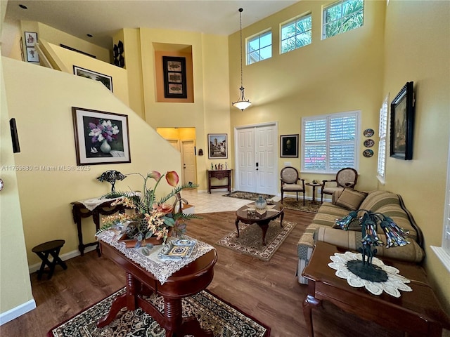 living room featuring a towering ceiling, baseboards, and wood finished floors