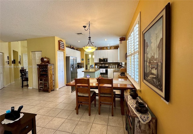 dining room with light tile patterned flooring, visible vents, and a textured ceiling