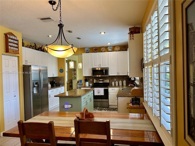 kitchen with a wealth of natural light, a kitchen island, appliances with stainless steel finishes, and a sink