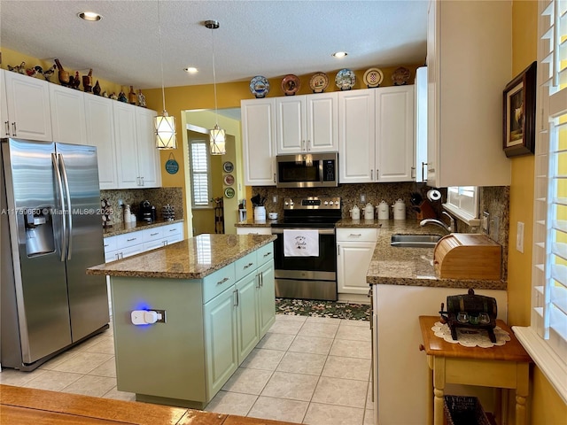 kitchen featuring a sink, a center island, white cabinetry, appliances with stainless steel finishes, and light tile patterned floors