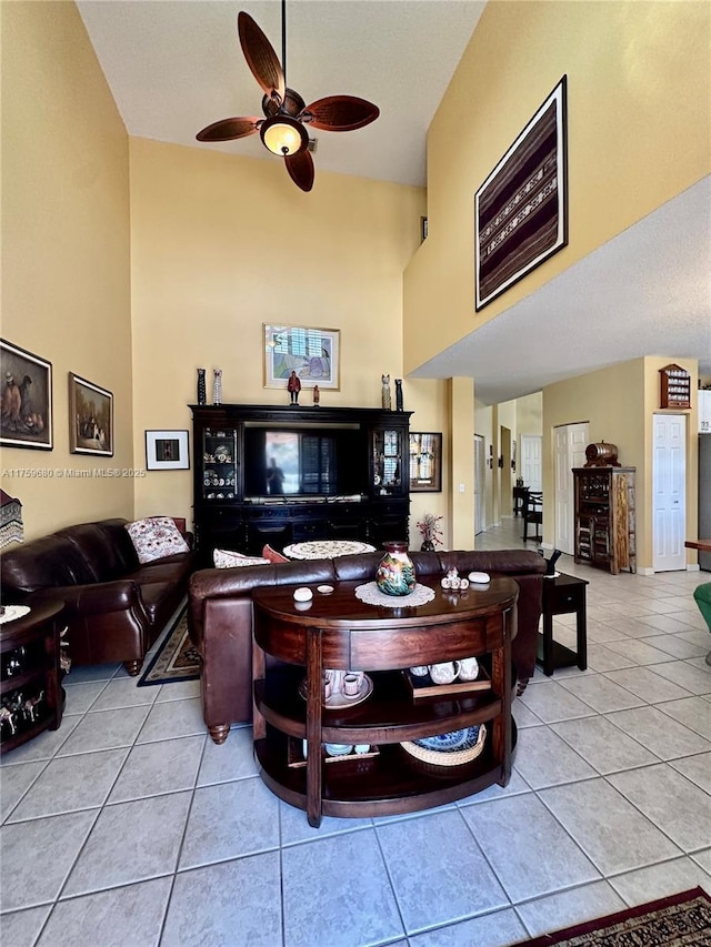 living area featuring tile patterned floors, a high ceiling, and a ceiling fan