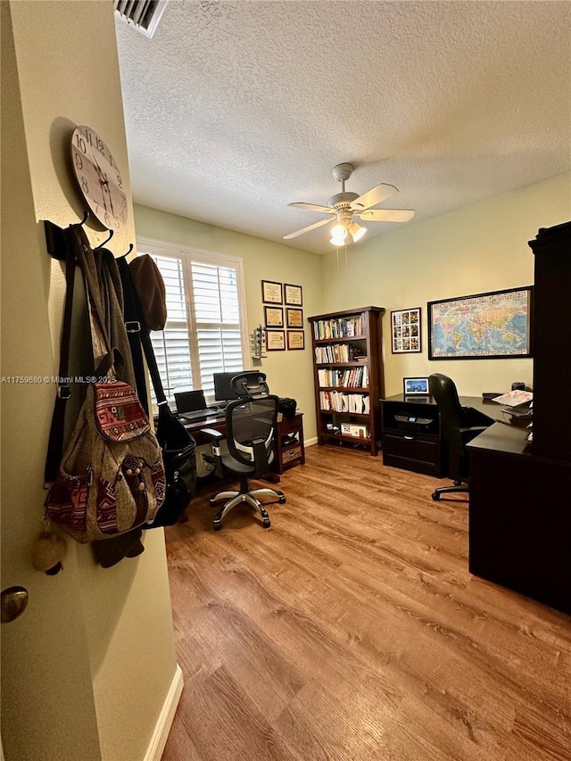 office featuring visible vents, a ceiling fan, a textured ceiling, wood finished floors, and baseboards