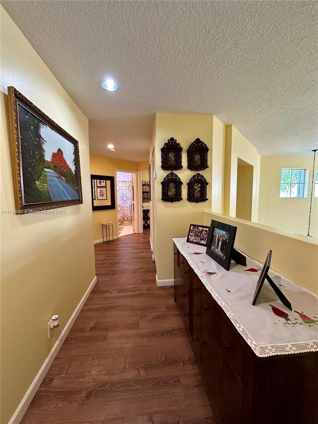 hall featuring baseboards, a textured ceiling, and dark wood-style floors