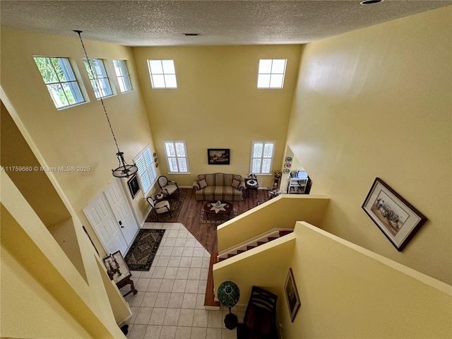 living room featuring light tile patterned floors, baseboards, a textured ceiling, and a high ceiling