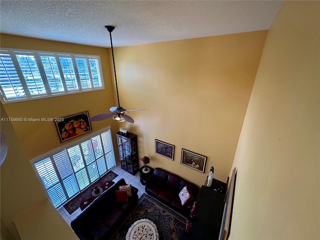 living area with tile patterned floors, a textured ceiling, and a ceiling fan