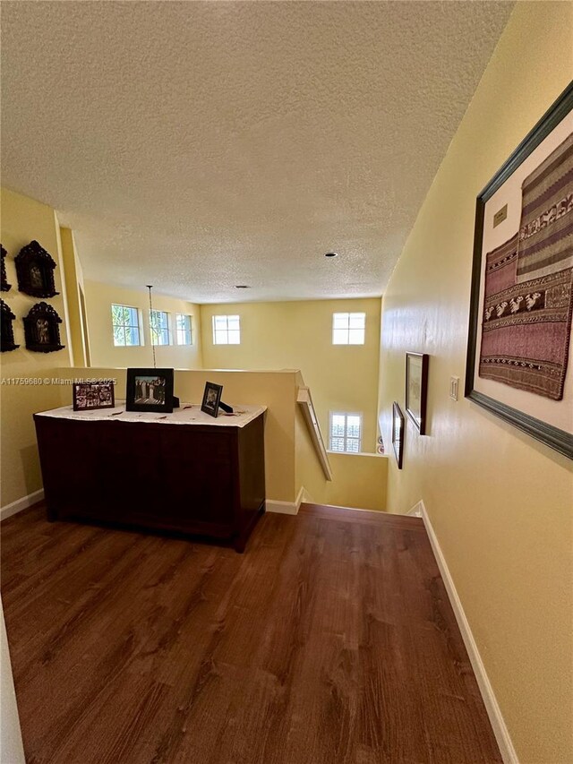 office featuring a textured ceiling, baseboards, and wood finished floors