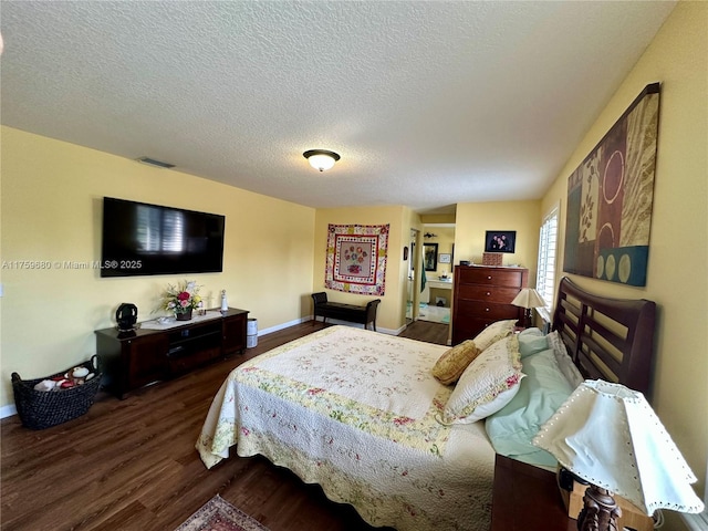 bedroom featuring visible vents, baseboards, a textured ceiling, and wood finished floors