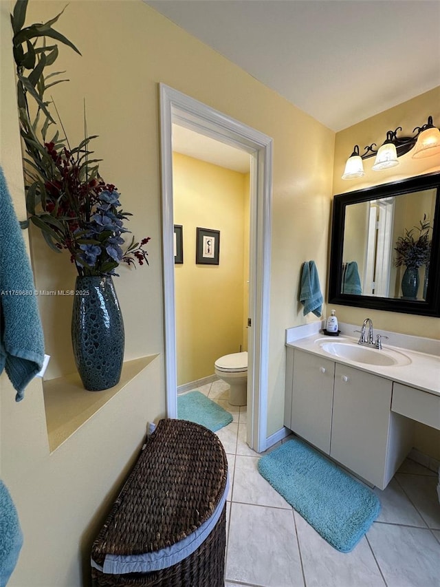 bathroom featuring tile patterned floors, baseboards, toilet, and vanity