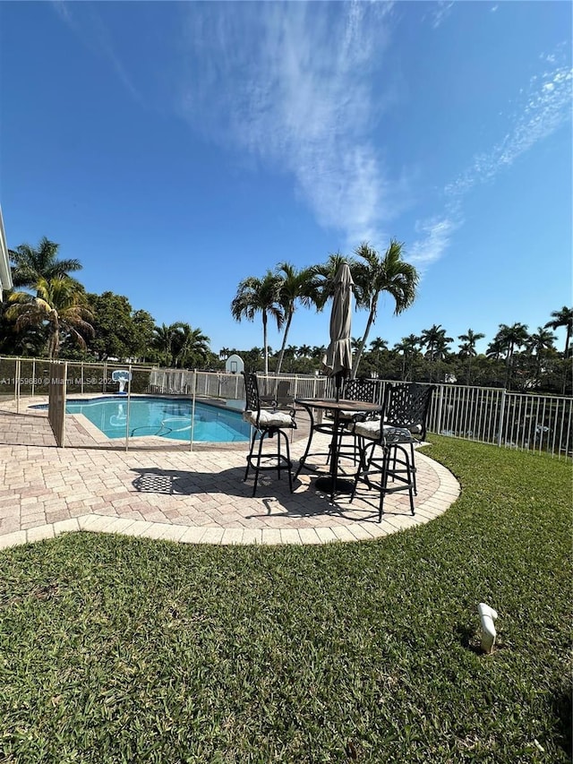 view of swimming pool with a patio, a yard, fence, and a fenced in pool