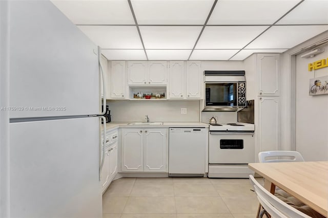 kitchen featuring light tile patterned floors, light countertops, white cabinetry, a sink, and white appliances