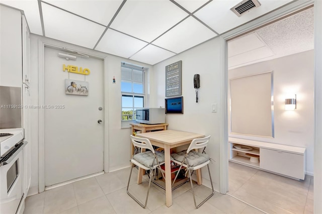 dining room with light tile patterned floors, visible vents, and a drop ceiling