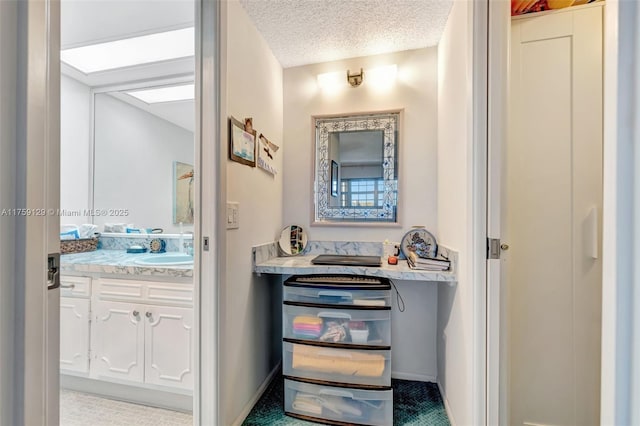 interior space with a textured ceiling, vanity, and baseboards