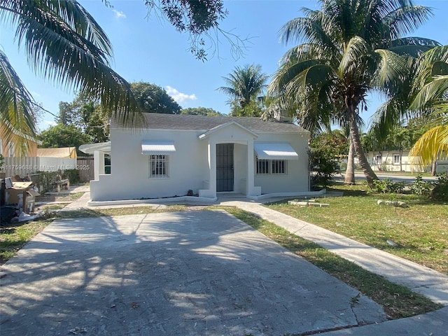 view of front of property featuring stucco siding, a front lawn, and fence