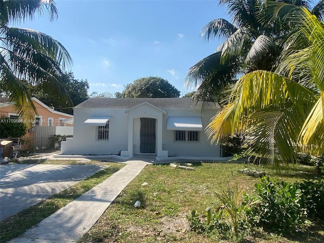 view of front of house with stucco siding and a front lawn