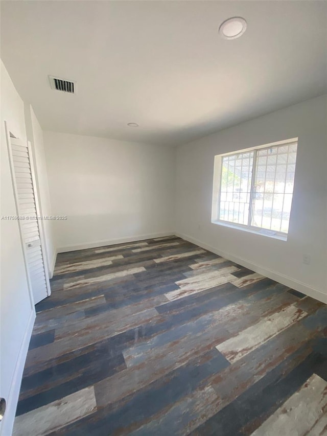 unfurnished room with visible vents, baseboards, and wood finished floors