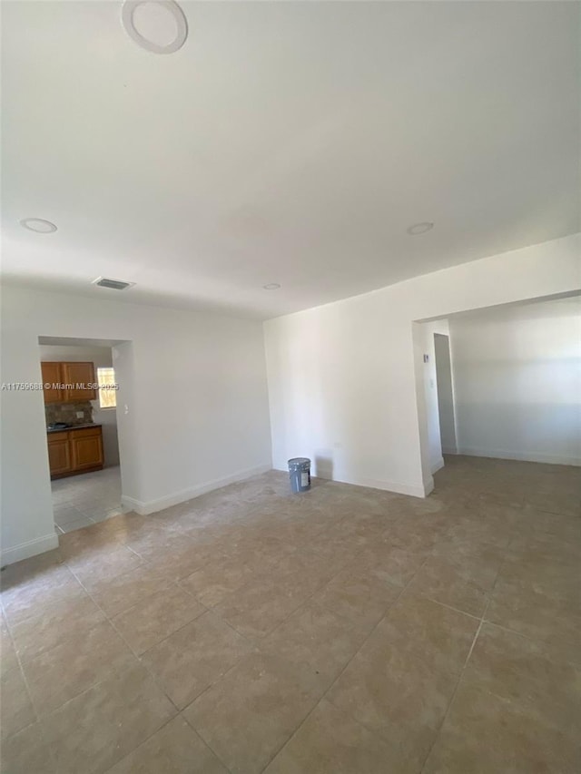 empty room with light tile patterned flooring, baseboards, and visible vents