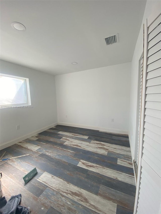 spare room with visible vents, baseboards, and wood finished floors