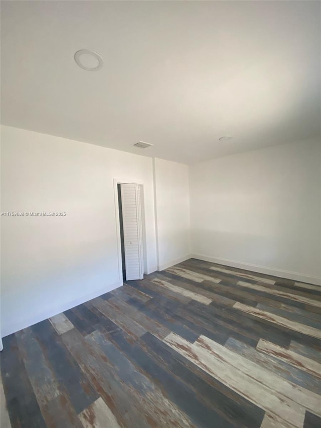 empty room featuring dark wood-type flooring and visible vents