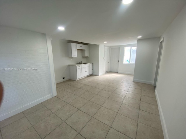 unfurnished room featuring light tile patterned floors, recessed lighting, baseboards, and brick wall