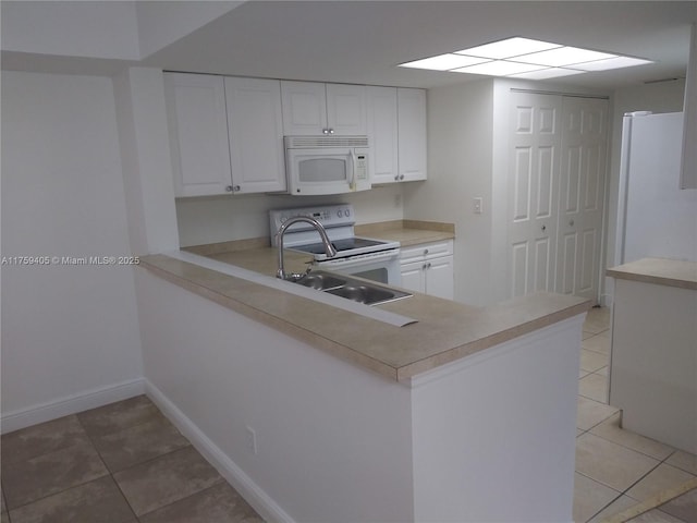 kitchen with light countertops, light tile patterned floors, white appliances, white cabinetry, and a sink