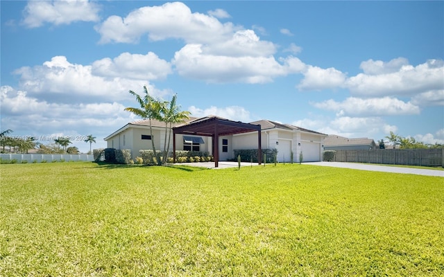 rear view of house with a garage, a lawn, driveway, and fence