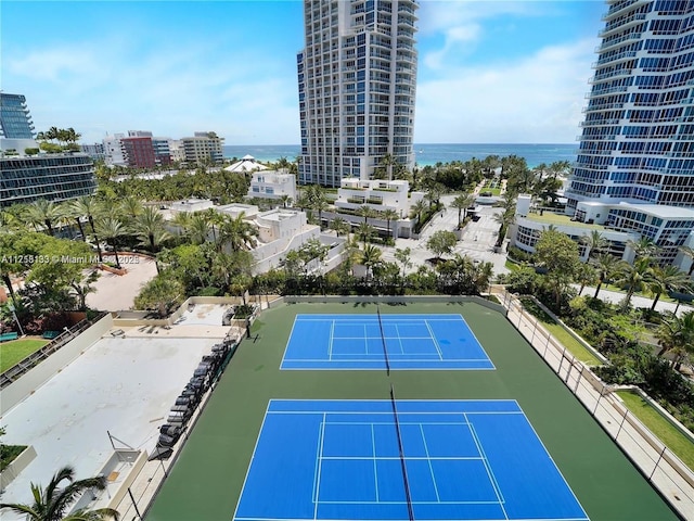 view of sport court with a view of city, a water view, and fence