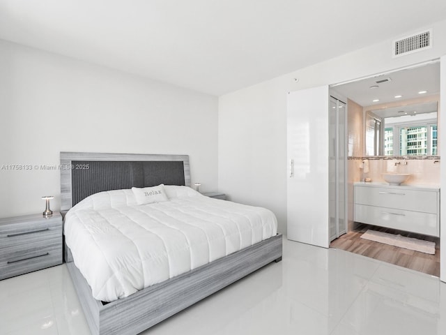 bedroom with connected bathroom, tile patterned flooring, visible vents, and a sink