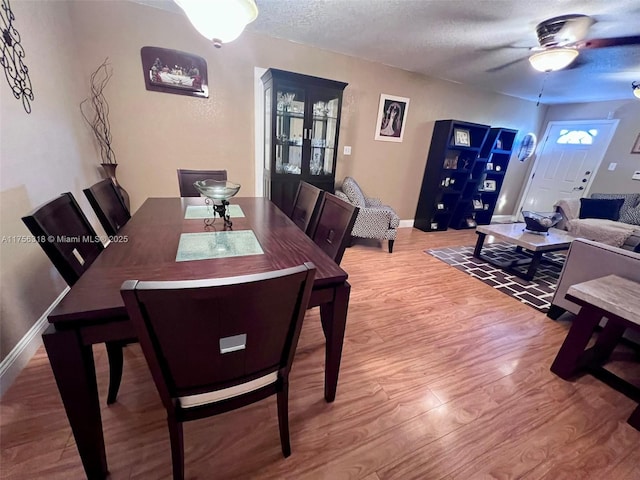 dining room with a textured ceiling, a ceiling fan, baseboards, light wood-style floors, and french doors