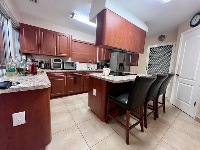 kitchen with stainless steel fridge with ice dispenser, a kitchen breakfast bar, a center island, light countertops, and light tile patterned flooring