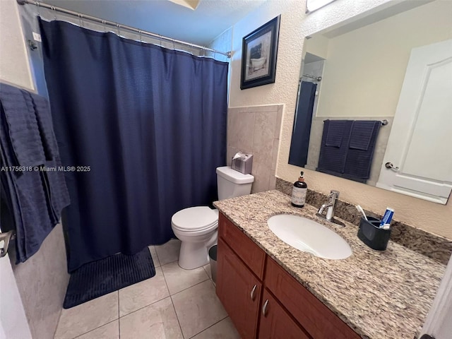 bathroom featuring toilet, tile patterned flooring, vanity, and a textured wall