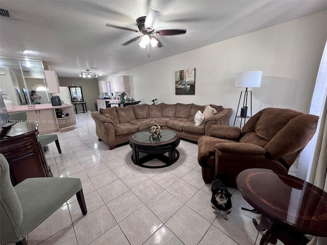 living room featuring a textured ceiling, ceiling fan, and light tile patterned floors