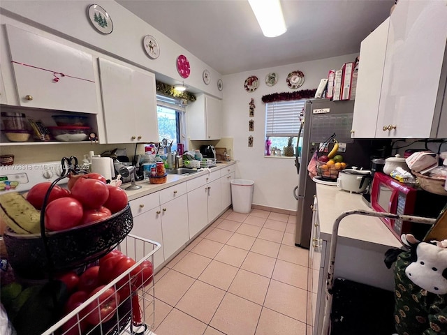 kitchen featuring light tile patterned floors, light countertops, a sink, and white cabinets